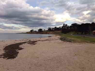 an empty beach on a cloudy day with the ocean in the foreground and clouds in the background