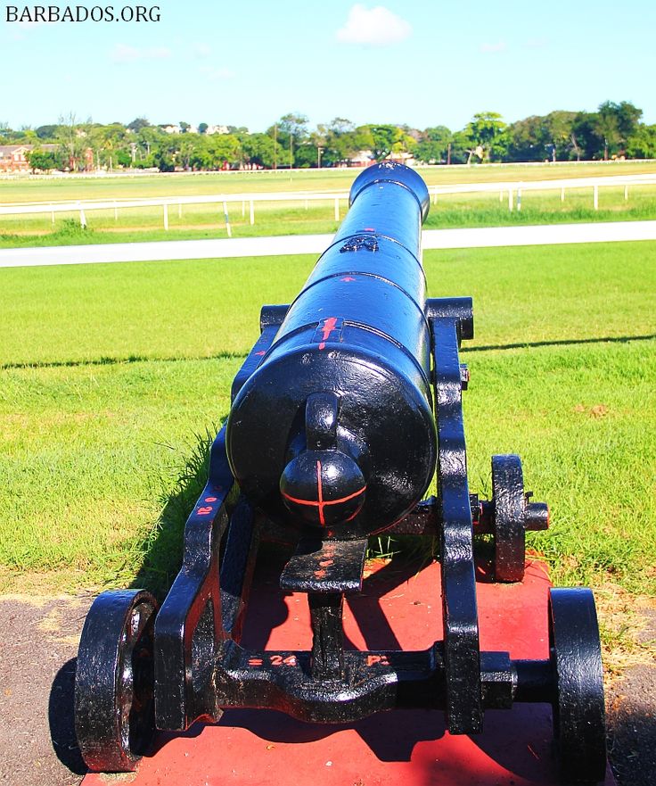 an old cannon sitting on top of a red platform in front of a grassy field