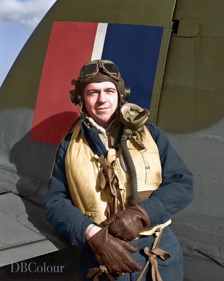 a man in an air force pilot's uniform standing next to a fighter jet