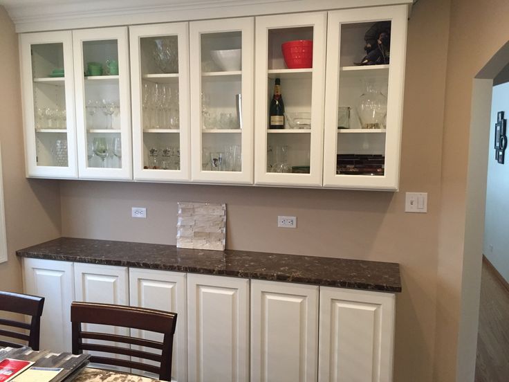 a kitchen with white cabinets and granite counter tops, along with a dining room table