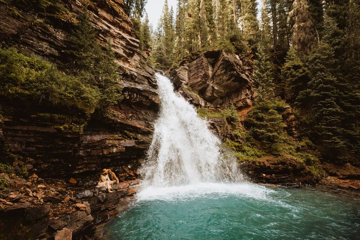 a person sitting on the edge of a waterfall