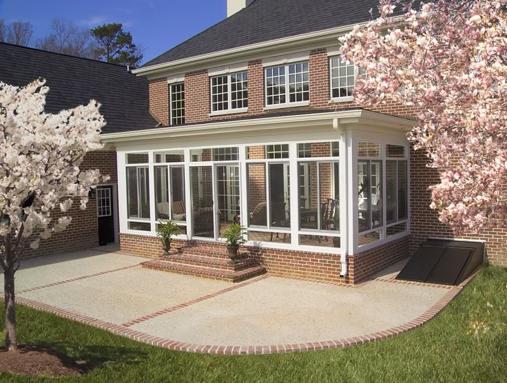 a large brick house with lots of windows on the front and side of it, surrounded by cherry blossom trees