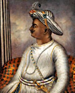 an old painting of a man in white and gold clothing sitting on a chair with his hands clasped