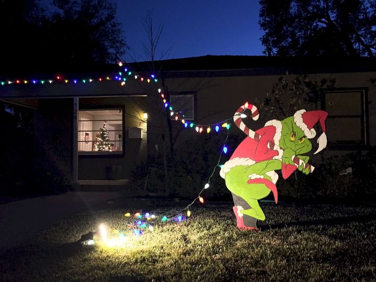 an inflatable christmas decoration is on the front lawn of a house at night