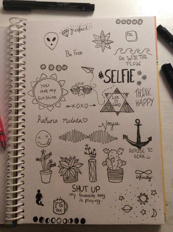 an open notebook with doodles on it and some pens next to it that says selfie