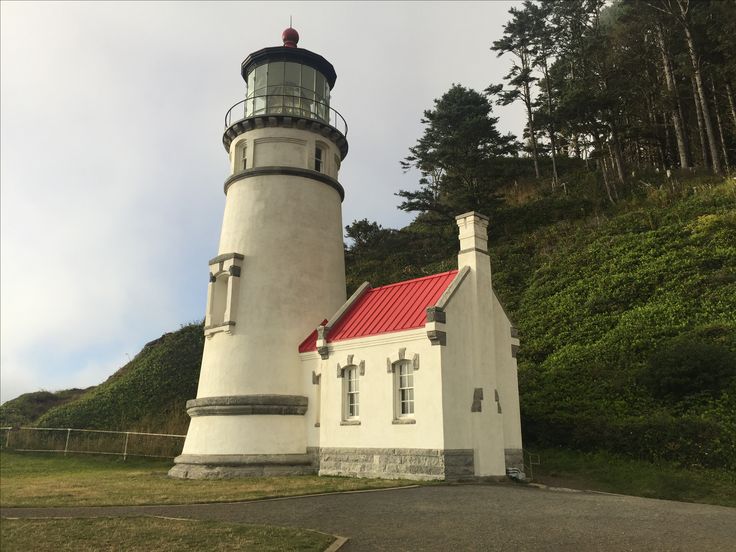 a white lighthouse with a red roof on a hill