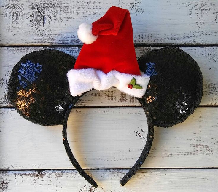 a mickey mouse ears hat on top of a white wooden surface with blue and gold flowers