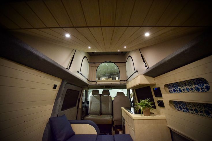 the interior of a van with blue couches and wood paneling on the walls