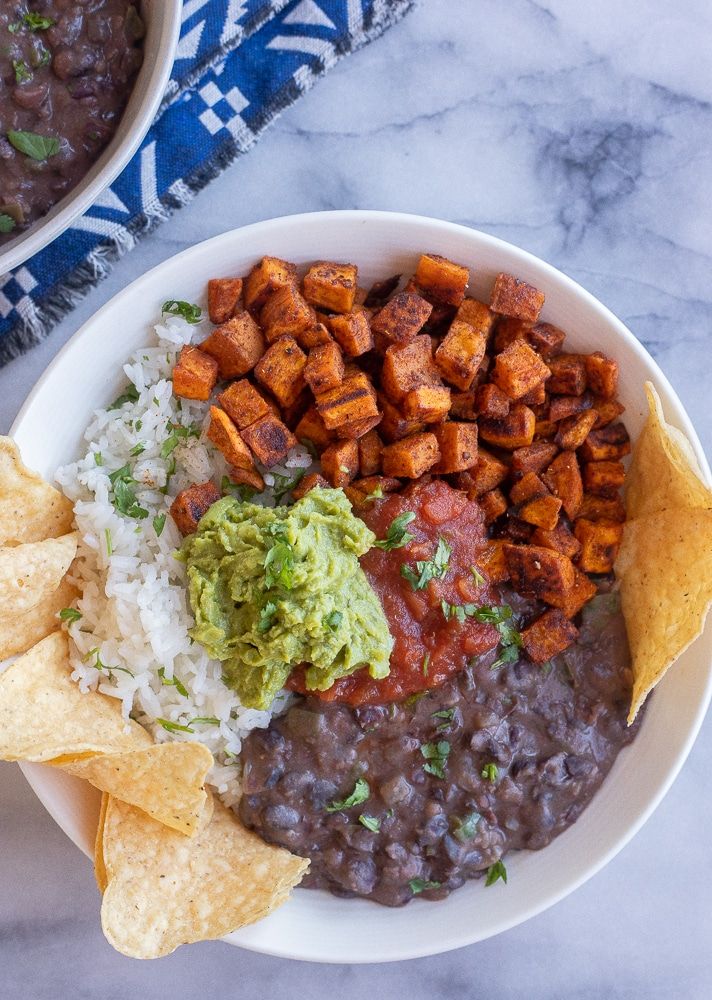 a bowl filled with beans, rice and guacamole next to tortilla chips