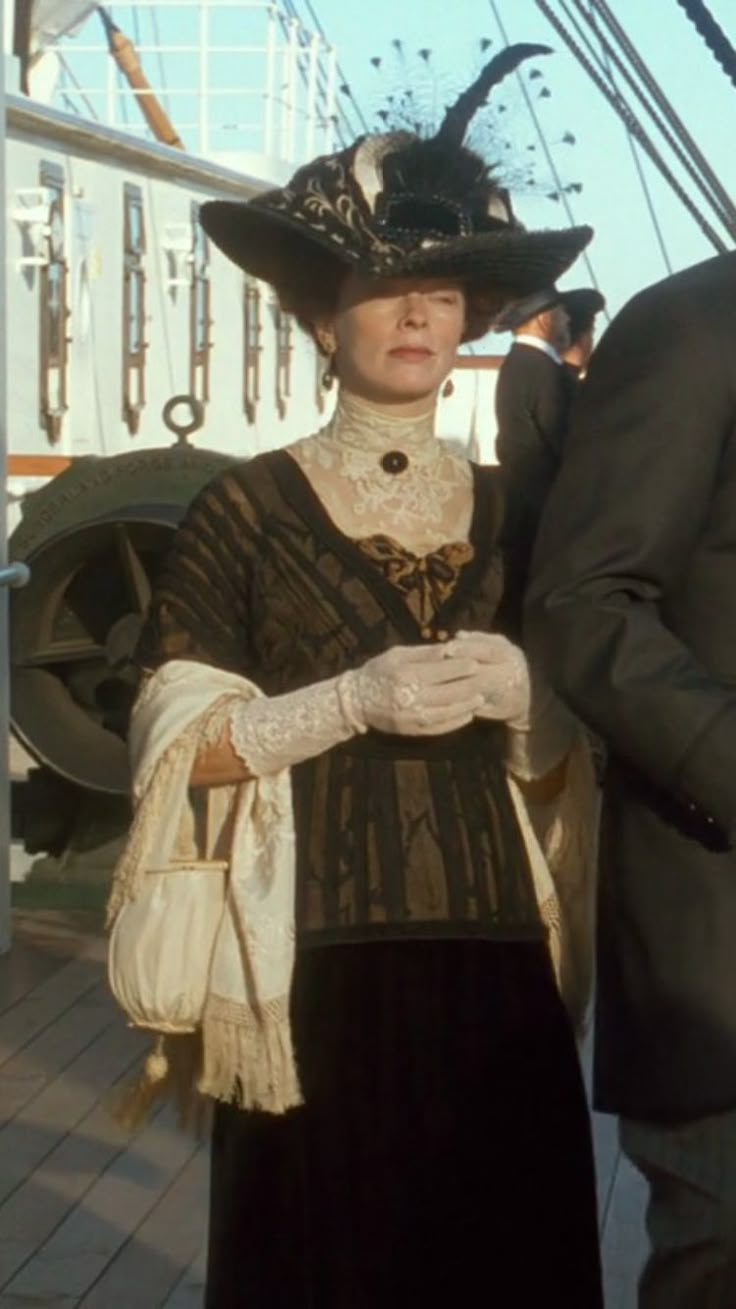 a man and woman dressed in period clothing on the deck of a ship, standing next to each other