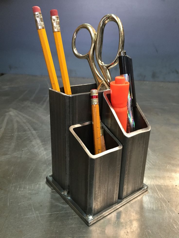 a metal holder with pencils, scissors and pens in it on a table top