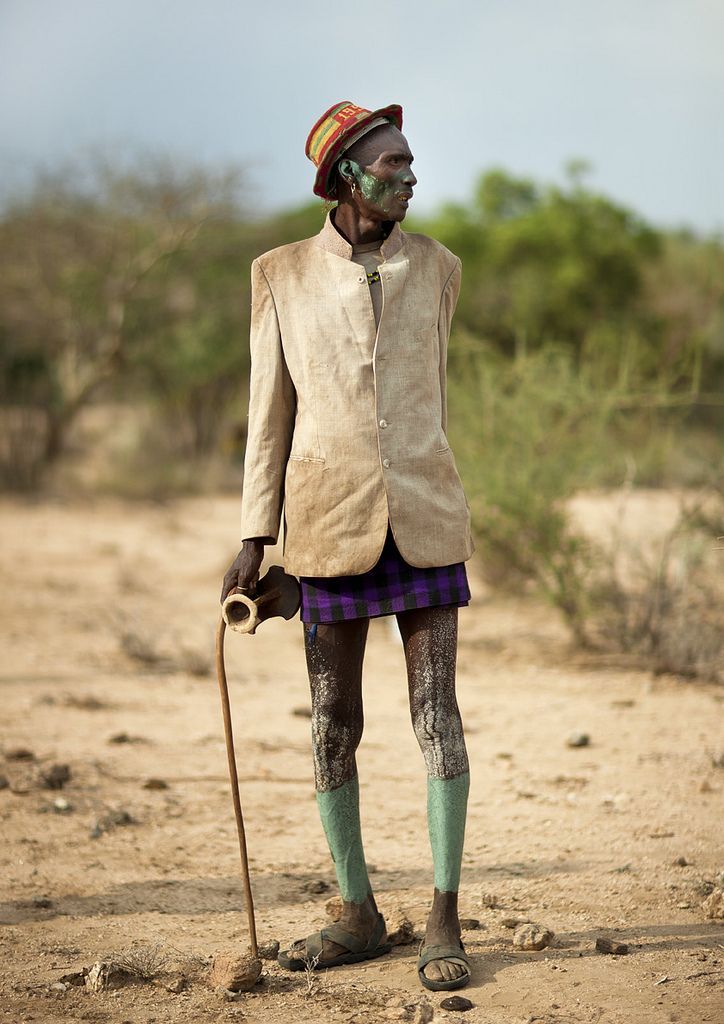 an old man standing in the dirt with a cane