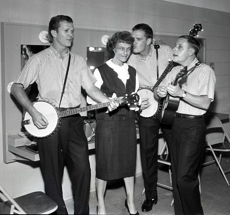 a group of people standing around each other with guitars and mandolins in their hands