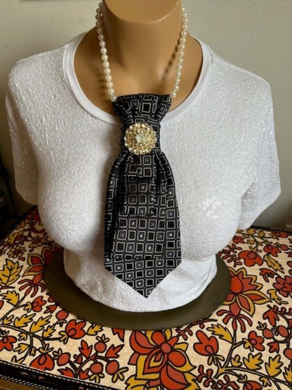 a mannequin wearing a white shirt and black tie with pearls on it's neck