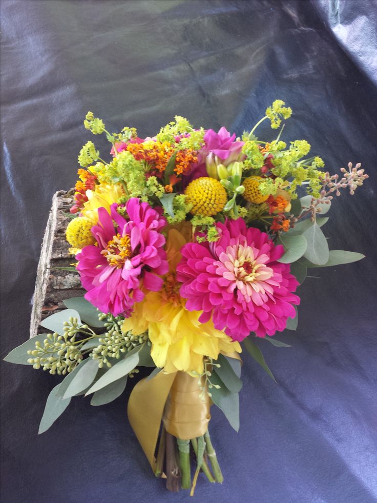 a bouquet of flowers sitting on top of a blue cloth covered table next to a piece of wood