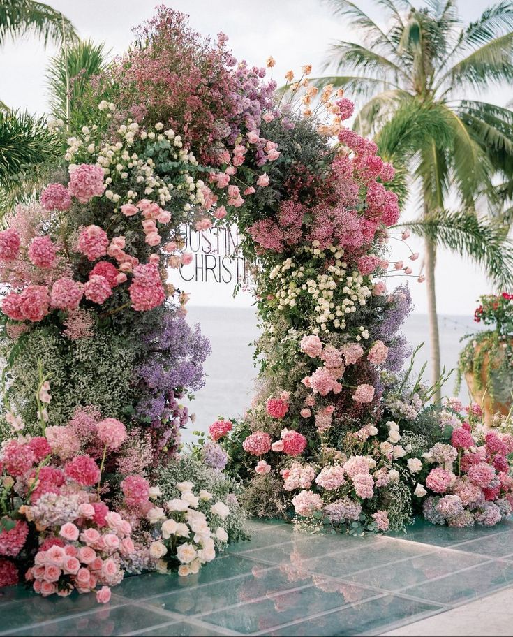 an arch made out of flowers with the words happy christmas written in front of it