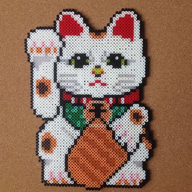 a cross stitch picture of a cat holding a carrot in it's paws, on a brown background