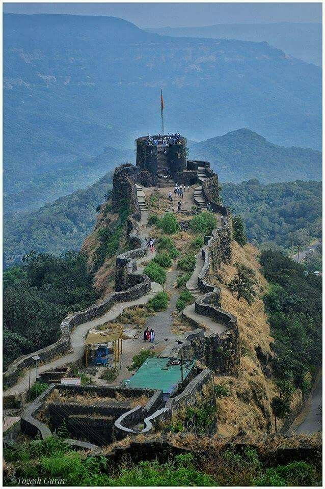 an old castle on top of a mountain with people walking up the hill to it