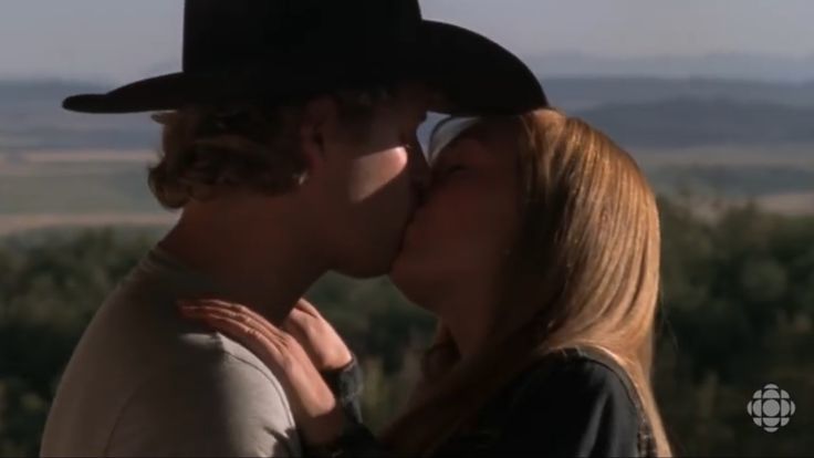 a man and woman kissing each other in front of trees