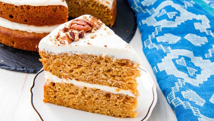 two slices of carrot cake with white frosting and pecans in the middle on a plate