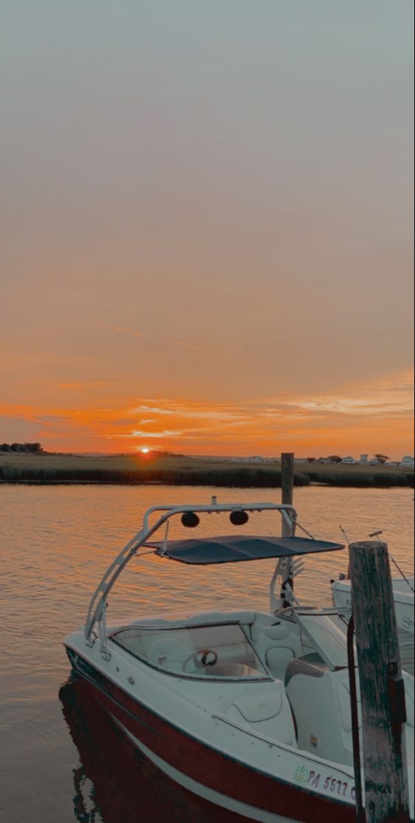 a boat is parked in the water at sunset