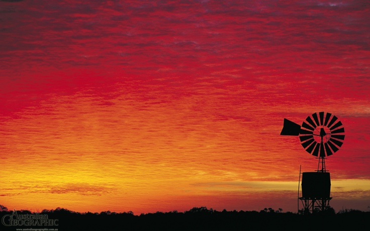 an orange and red sunset with a windmill in the foreground