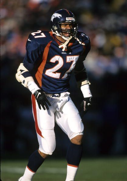 a football player is standing on the field with his hands in his pockets and wearing a helmet