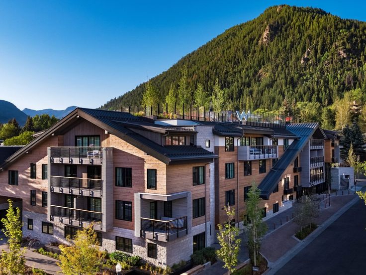 an aerial view of a building with mountains in the back ground and trees on either side