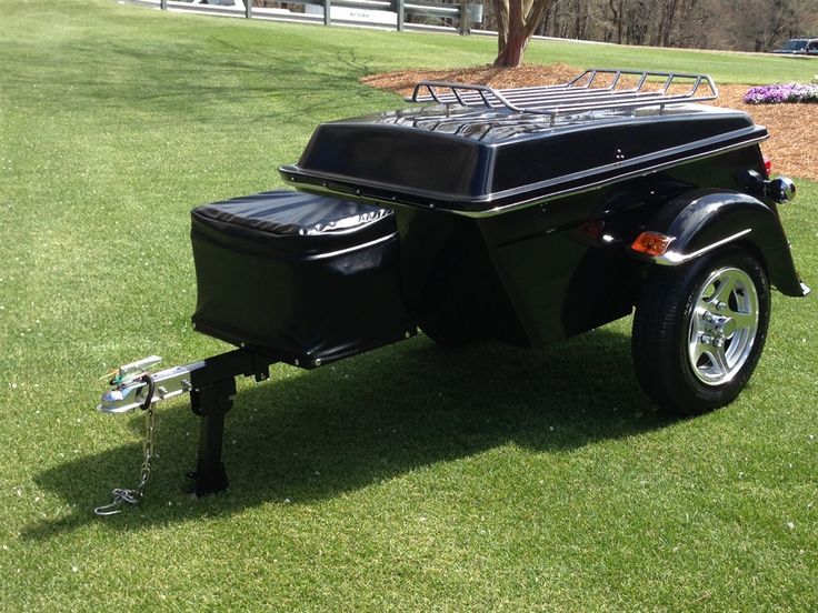 a black motorcycle trailer parked on top of a lush green field