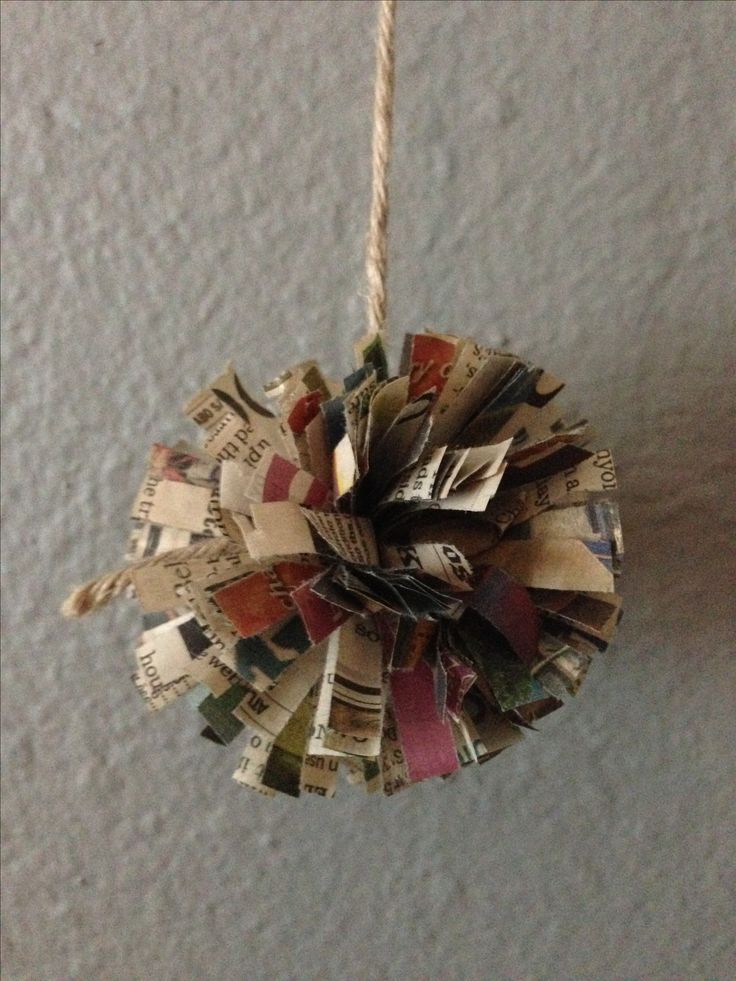 an ornament made out of old newspapers hanging from a rope on the wall