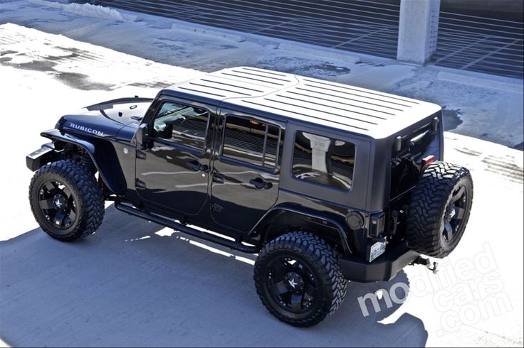 the jeep is parked on the side of the road in front of a building with snow