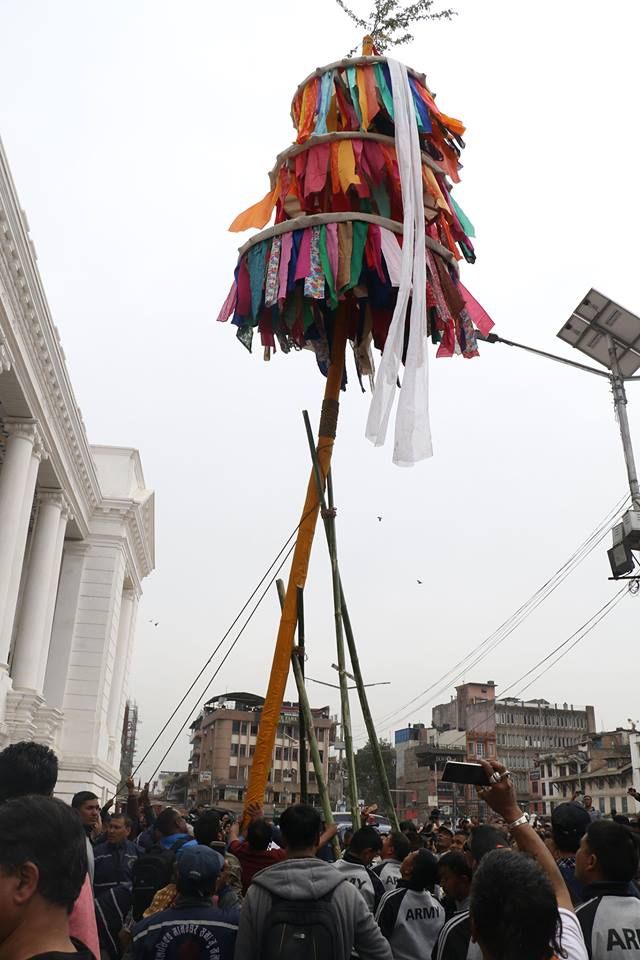 a large group of people walking down a street next to tall poles with ribbons on them