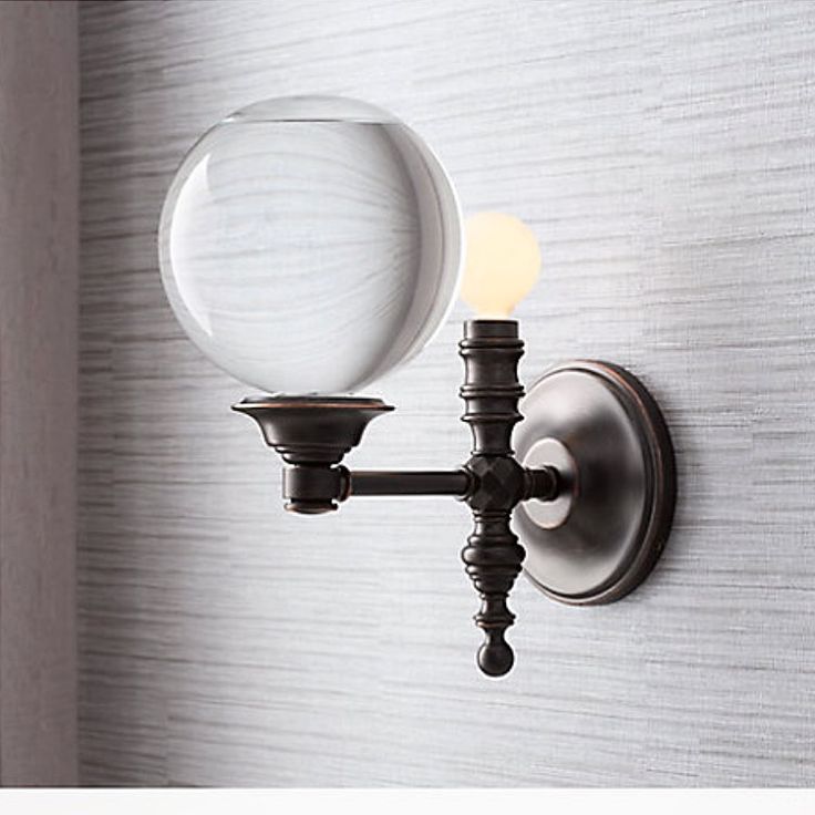 a wall light with a glass ball on the front and back of it's arm