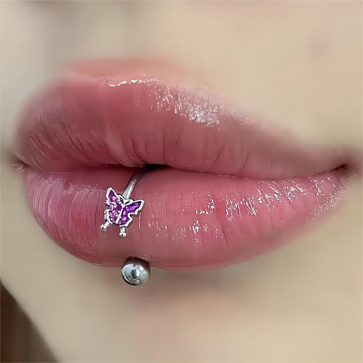 a woman's lips are covered in pink lipstick and silver jewelry with a butterfly on the lip