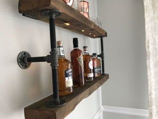 some bottles are sitting on the shelf in front of the mirror and light fixture that is attached to the wall