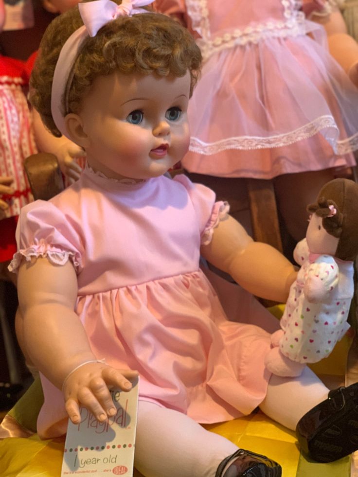 a baby doll sitting on top of a table next to other dolls