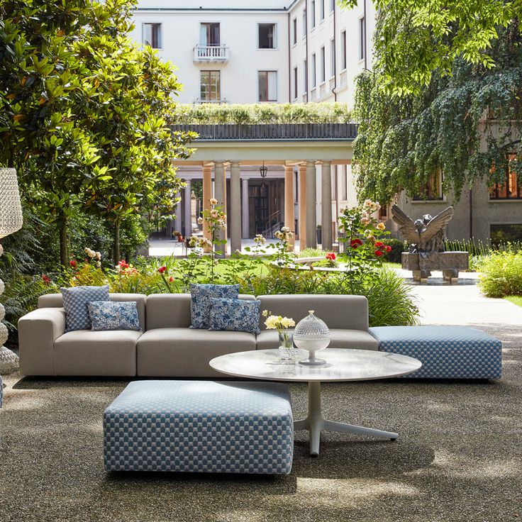 a living room filled with furniture and lots of greenery in front of a building