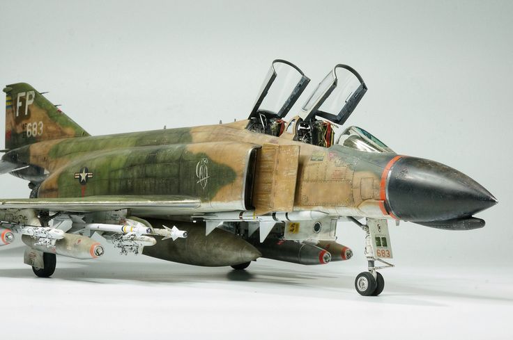 an old model fighter jet sitting on top of a white surface with its door open