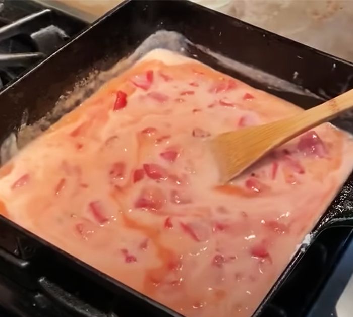 a pan filled with food sitting on top of a stove next to a wooden spatula