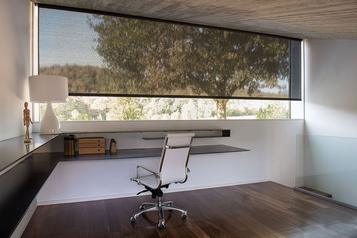 an office chair sitting in front of a large window with trees on the outside wall