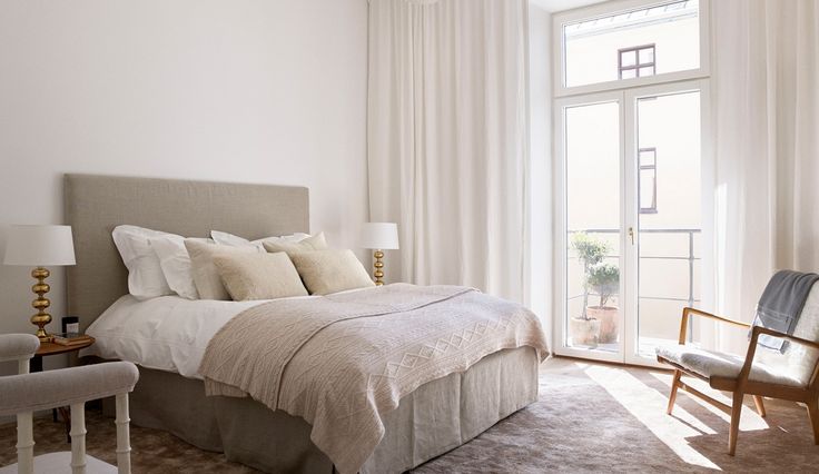 a bedroom with a bed, chair and large window in it's center area