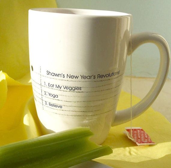 a white coffee cup sitting on top of a table next to a celery