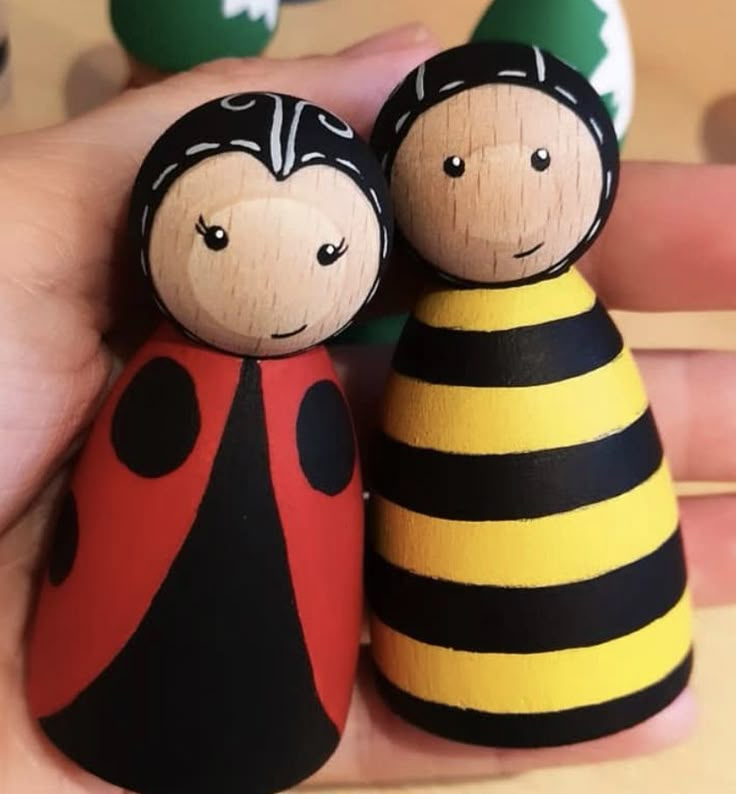 two wooden peg dolls are sitting next to each other