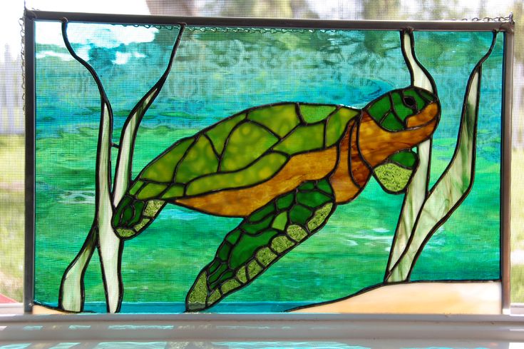 a stained glass window with a turtle swimming in the water