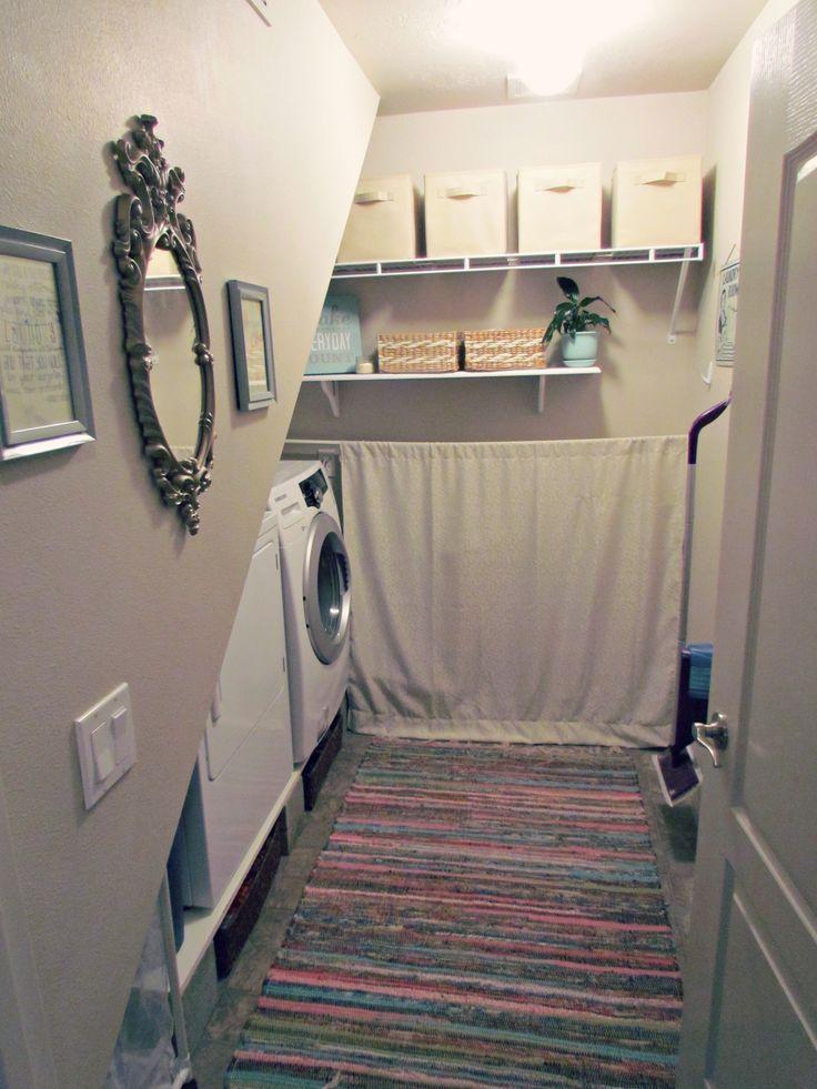 a washer and dryer in a small room next to a doorway with shelves on the wall