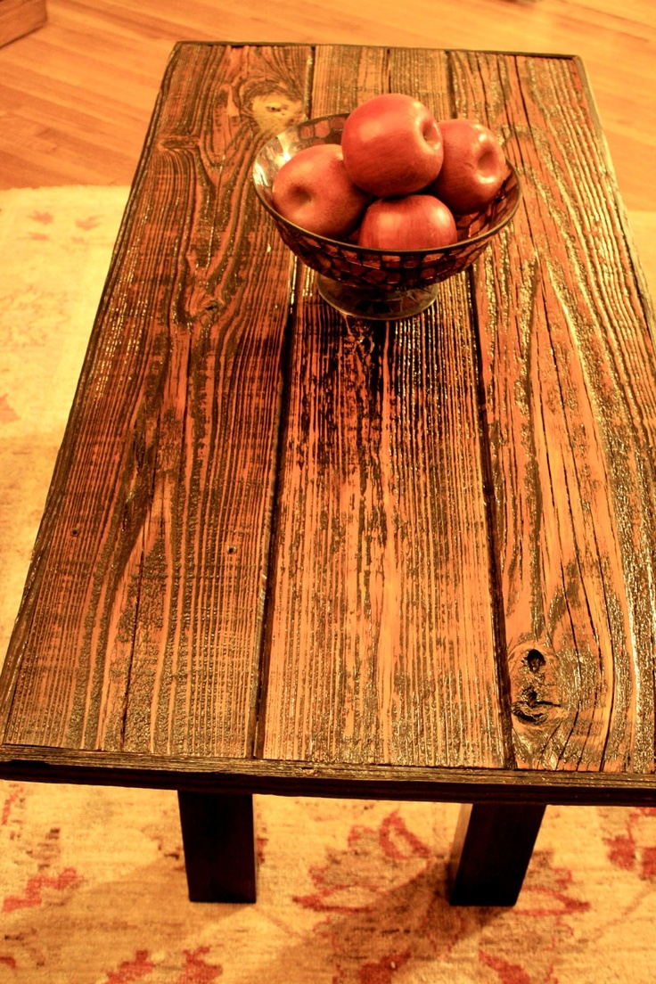 a wooden table topped with apples on top of a rug