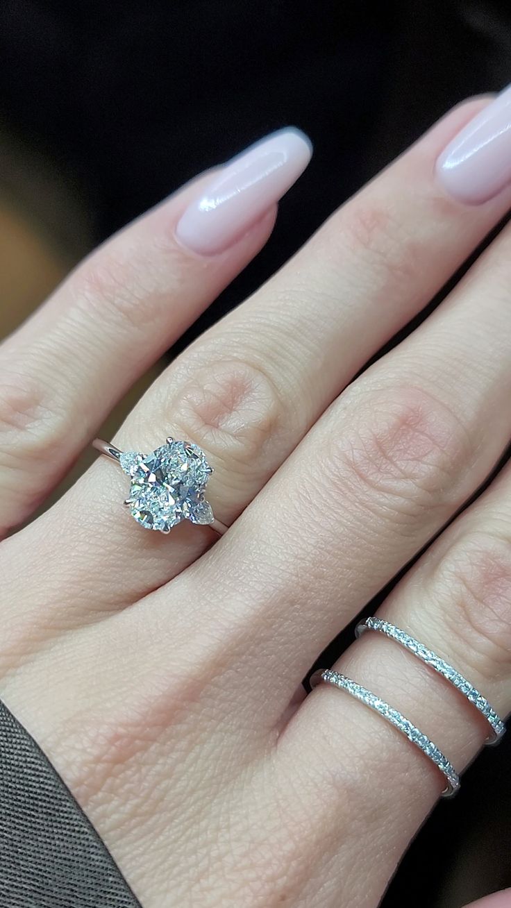 a woman's hand with two rings on it and a diamond ring in the middle