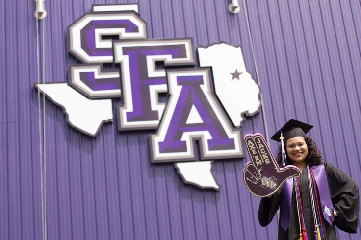 a woman in purple graduation gown holding up a sign that reads, texas a & m