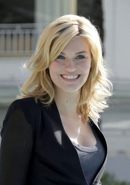 a woman with blonde hair is smiling for the camera while wearing a black blazer