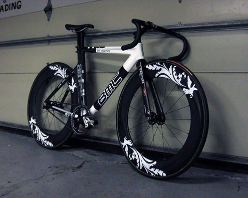 the bike is leaning against the wall in front of the garage door and it's black and white paint